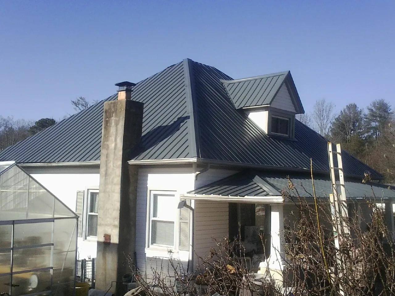 Dark blue standing seam metal roof on a white farmhouse with dormer — Slate & Tile Roof Repair by Roofing Brothers in Glenarm