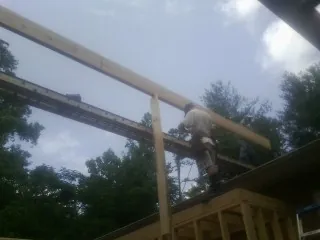 Carpenter setting a ridge beam over a new addition frame — Ice Dam Removal by Roofing Brothers in Glenarm