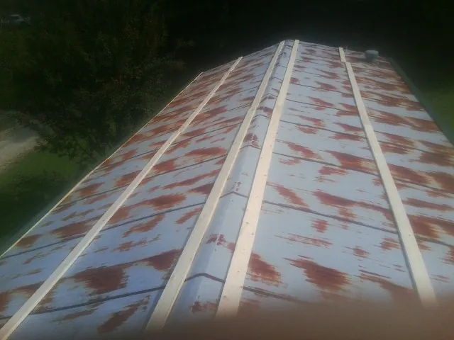 Rusted metal roof panels with new wood purlins before replacement — Storm Damage Roof Repair in Glenarm by Roofing Brothers