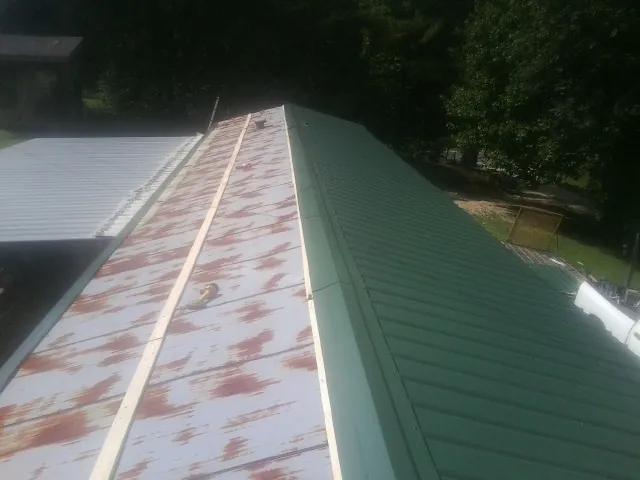 Old rusted panels beside newly installed green metal roofing — Wind Damage Roof Repair by Roofing Brothers in Glenarm