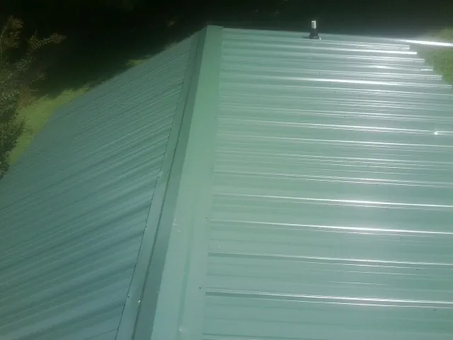 New green metal panels meeting at the ridge of a roof — Flat Roof Repair work by our crew in Glenarm