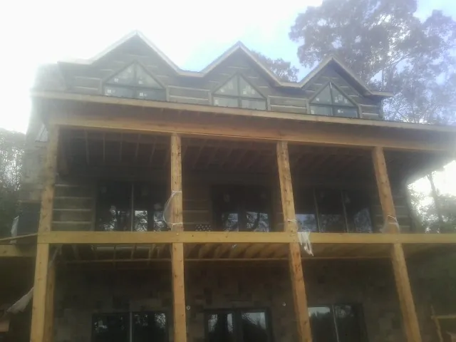 Dormers and porch framing on a large log home under construction — Roof Coating work by our crew in Glenarm