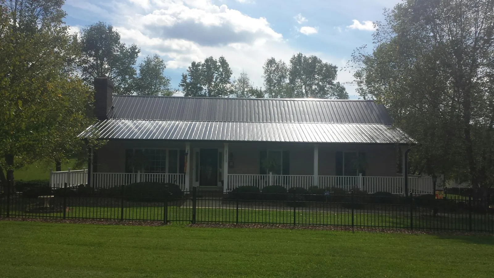 Gray metal roof on a brick ranch with a full width front porch — Gutter Guard Installation work by our crew in Glenarm