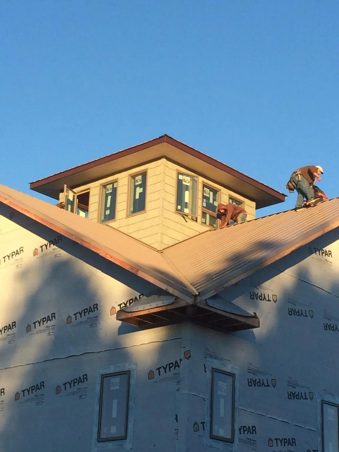 Roofers working around a rooftop cupola on a new metal roof at sunset — Roof Waterproofing in Glenarm by Roofing Brothers